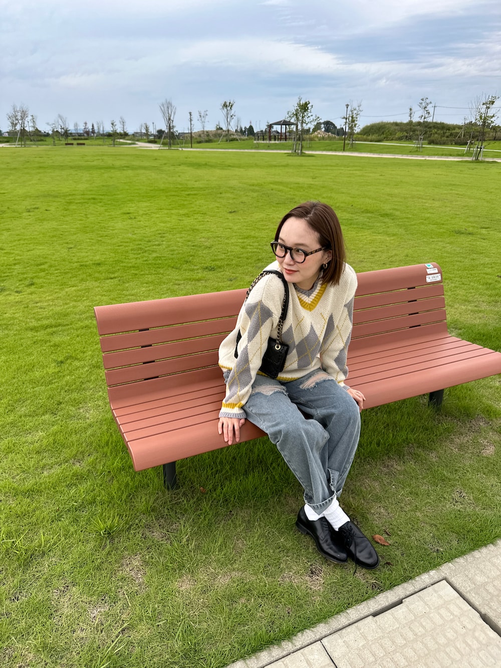 ブルー系のデニムパンツ、ベージュ系のニット/セーター、ブラウン系のメガネを着用したレディースの秋コーディネートの3枚目の写真