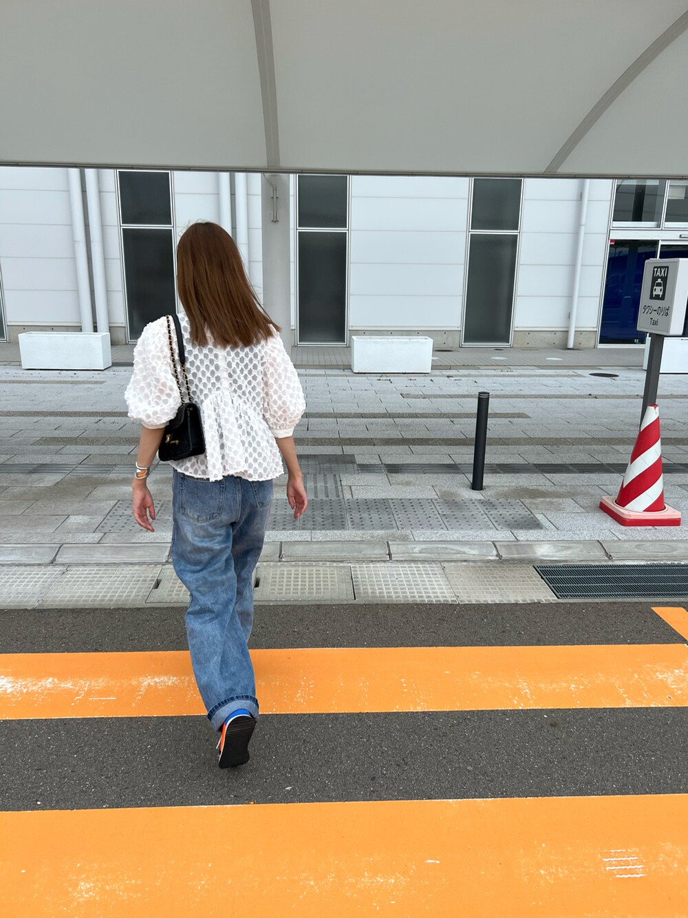 オレンジ系のシューズ、ブルー系のデニムパンツ、ホワイト系のシャツ/ブラウスを着用したレディースの夏コーディネートの3枚目の写真