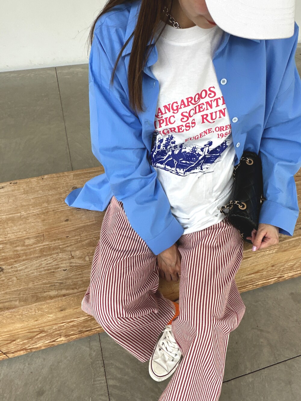 ブルー系のシャツ/ブラウス、レッド系のパンツ、ホワイト系のキャップを着用したレディースの春コーディネートの2枚目の写真