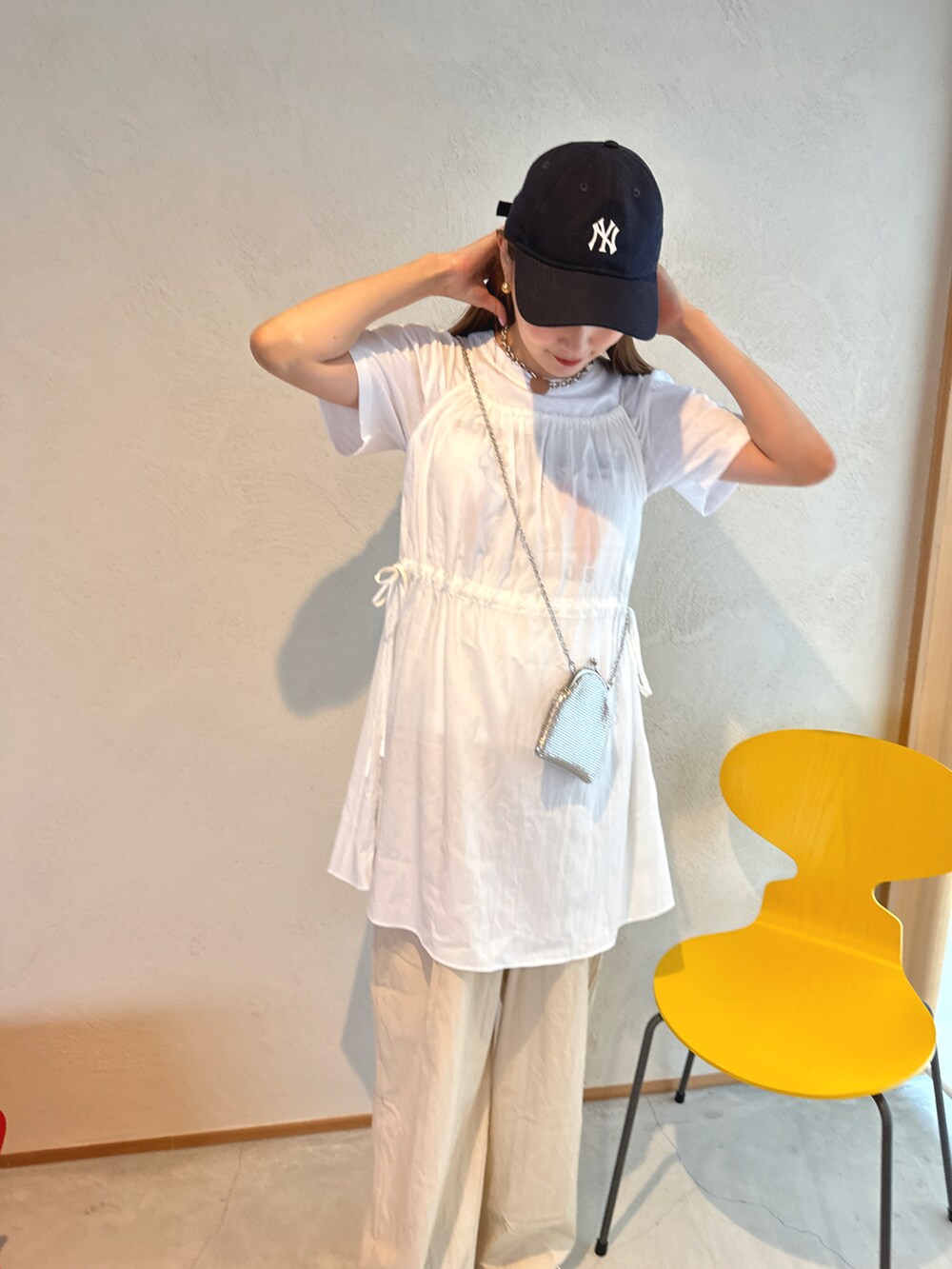 グリーン系のスニーカー、ベージュ系のパンツ、ホワイト系のワンピース/ドレスを着用したレディースの春コーディネートの2枚目の写真