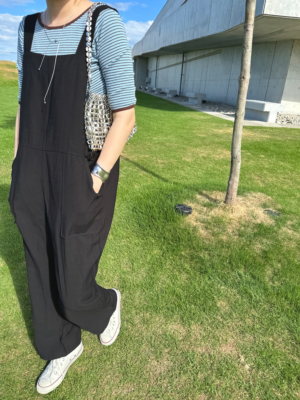 ブラック系のオールインワン・サロペット、ブルー系のトップス、シルバー系のバッグを着用したレディースの秋コーディネートの3枚目の写真