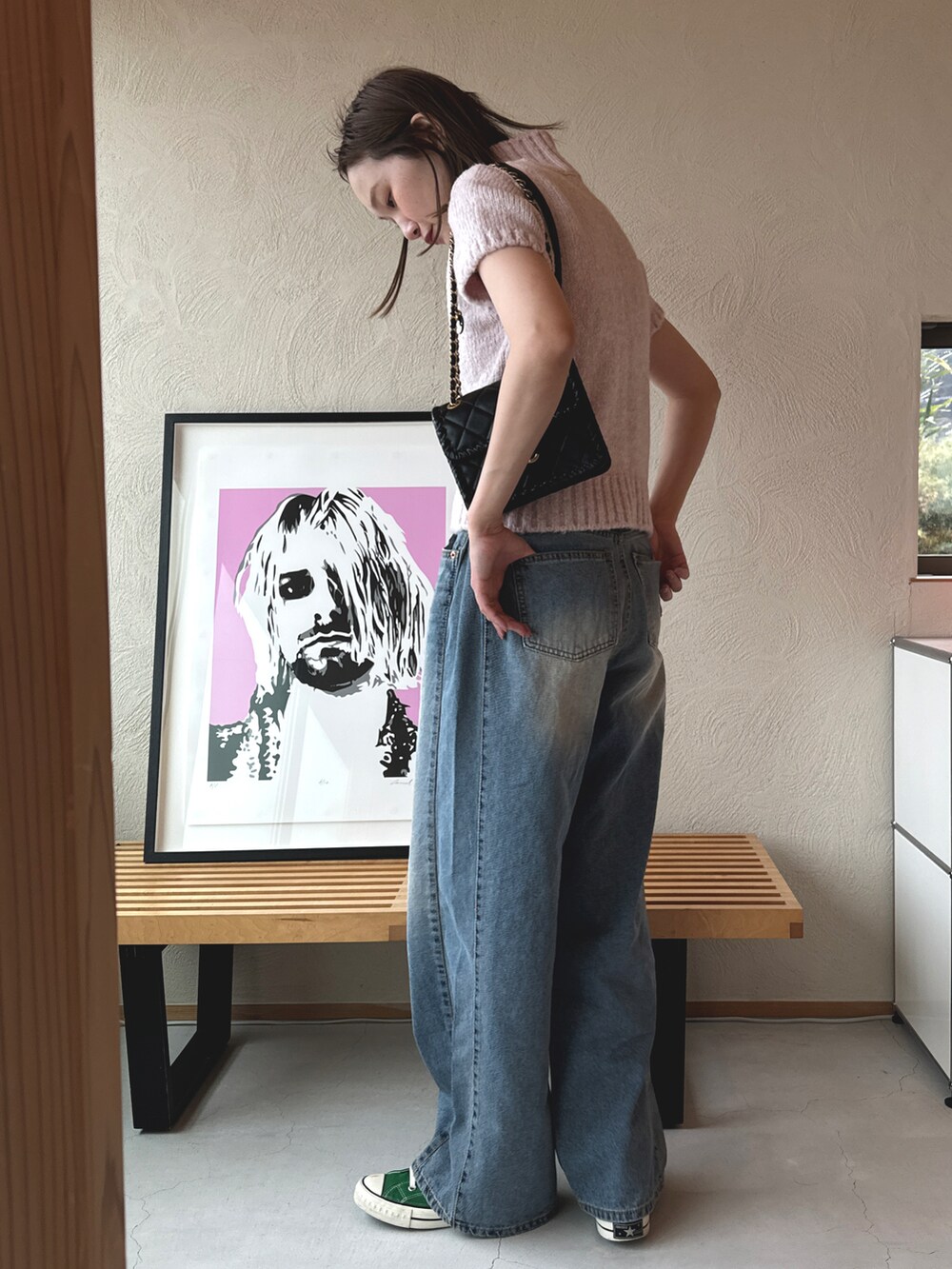 ブルー系のデニムパンツ、ピンク系のニット/セーター、グリーン系のスニーカーを着用したレディースの春コーディネートの2枚目の写真