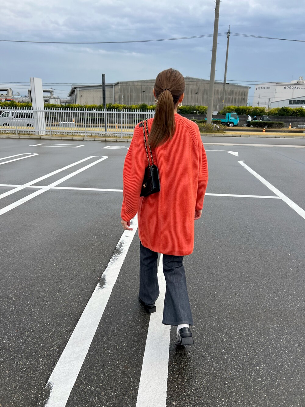 ブラック系のローファー、ブラック系のデニムパンツ、オレンジ系のチュニックを着用したレディースの秋コーディネートの3枚目の写真