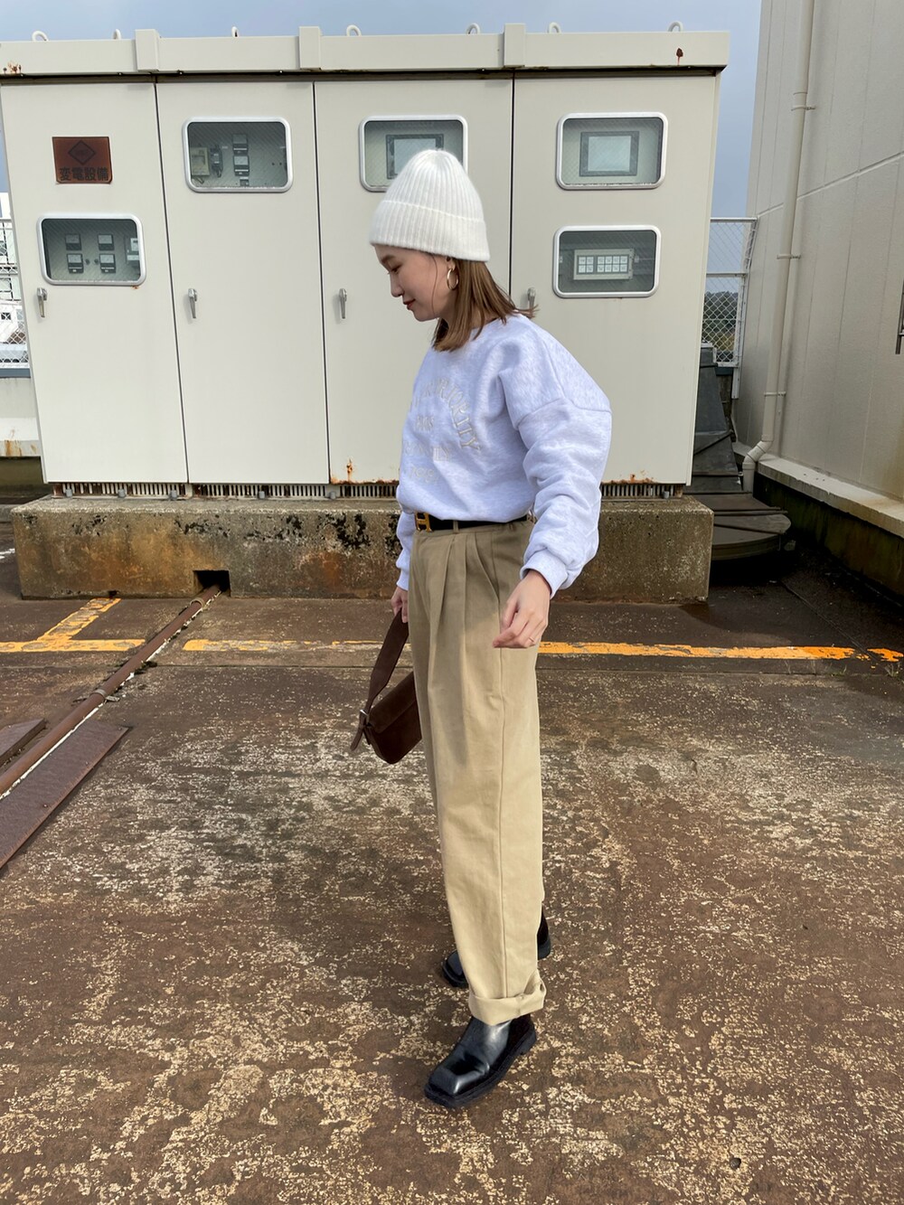 ベージュ系のチノパンツ、ブラック系のブーツ、グレー系のスウェットを着用したレディースの冬コーディネートの2枚目の写真