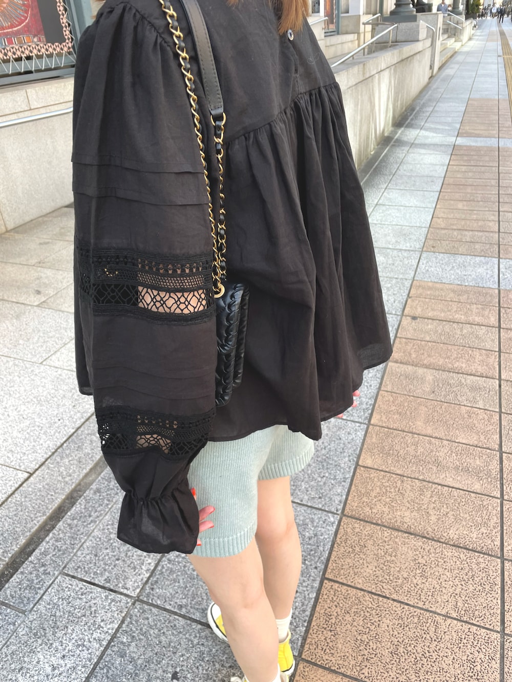 イエロー系のスニーカー、ブルー系のパンツ、ブラック系のシャツ/ブラウスを着用したレディースの春コーディネートの3枚目の写真