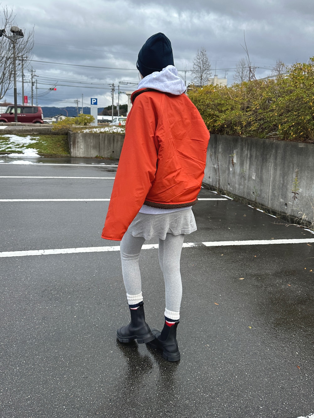 グレー系のスカート、ブラック系のブーツ、オレンジ系のジャケット/アウターを着用したレディースの冬コーディネートの3枚目の写真