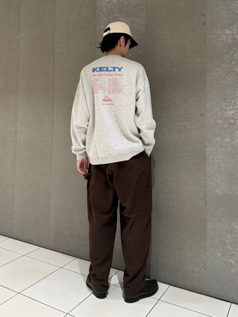 グレー系のスウェット、ブラウン系のその他パンツ、ホワイト系のキャップを着用したメンズの秋コーディネートの2枚目の写真