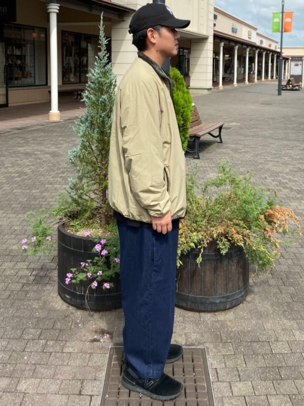 ブルー系のデニムパンツ、ブラック系のTシャツ/カットソー、ベージュ系のブルゾンを着用したメンズの秋コーディネートの2枚目の写真