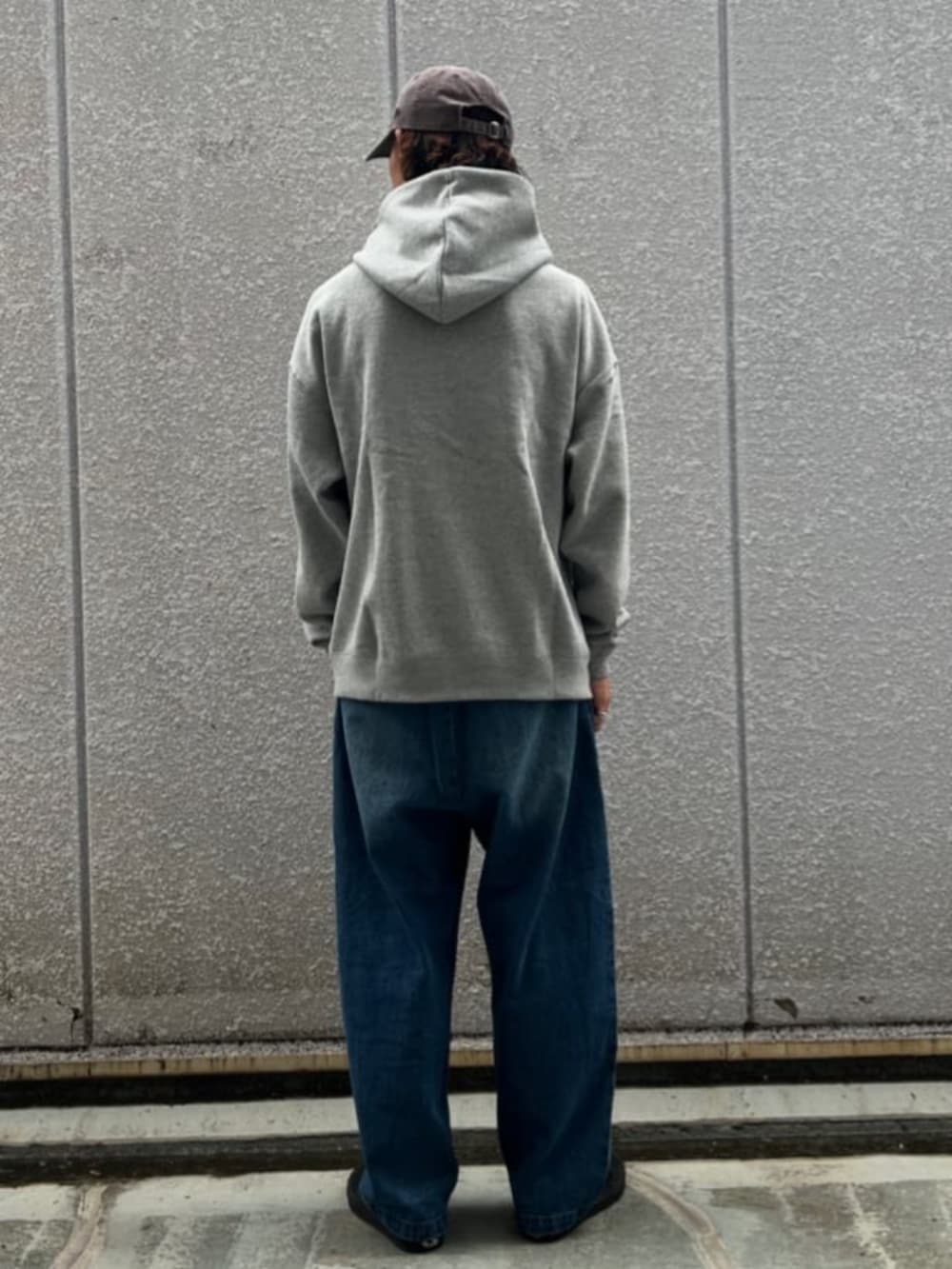 グレー系のパーカー、ブルー系のデニムパンツを着用したメンズの秋コーディネートの3枚目の写真
