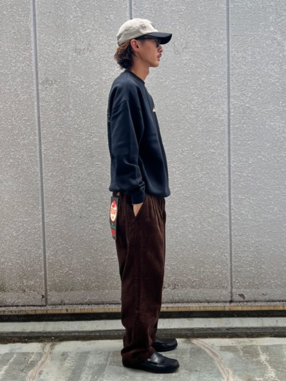 ブラック系のスウェット、ブラウン系のその他パンツ、ホワイト系のキャップを着用したメンズの秋コーディネートの2枚目の写真