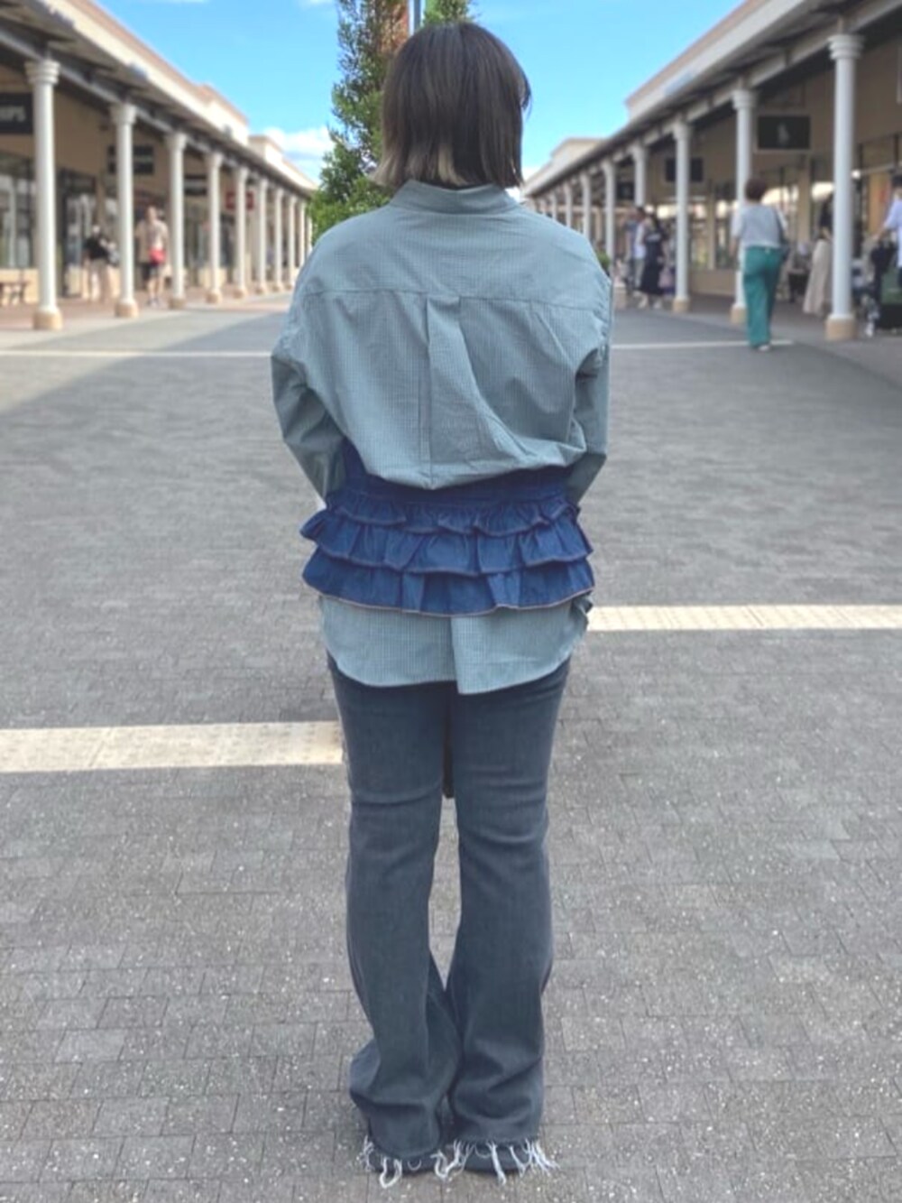 ベージュ系のショルダーバッグ、ブルー系のシャツ/ブラウス、ブラック系のデニムパンツを着用したレディースの夏コーディネートの3枚目の写真