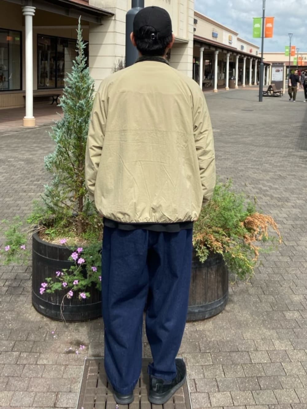 ブルー系のデニムパンツ、ブラック系のTシャツ/カットソー、ベージュ系のブルゾンを着用したメンズの秋コーディネートの3枚目の写真