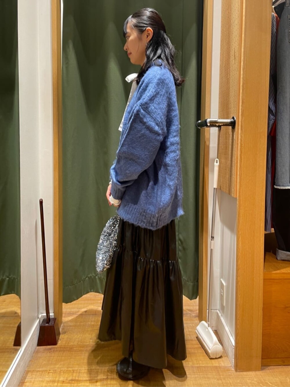 ブラック系のスカート、ブルー系のニット/セーター、シルバー系のショルダーバッグを着用したレディースの夏コーディネートの2枚目の写真