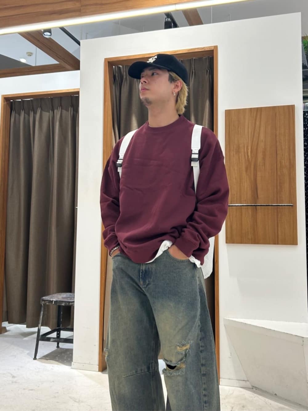 レッド系のスウェット、ブルー系のデニムパンツ、ブラック系のキャップを着用したメンズの秋コーディネートの3枚目の写真