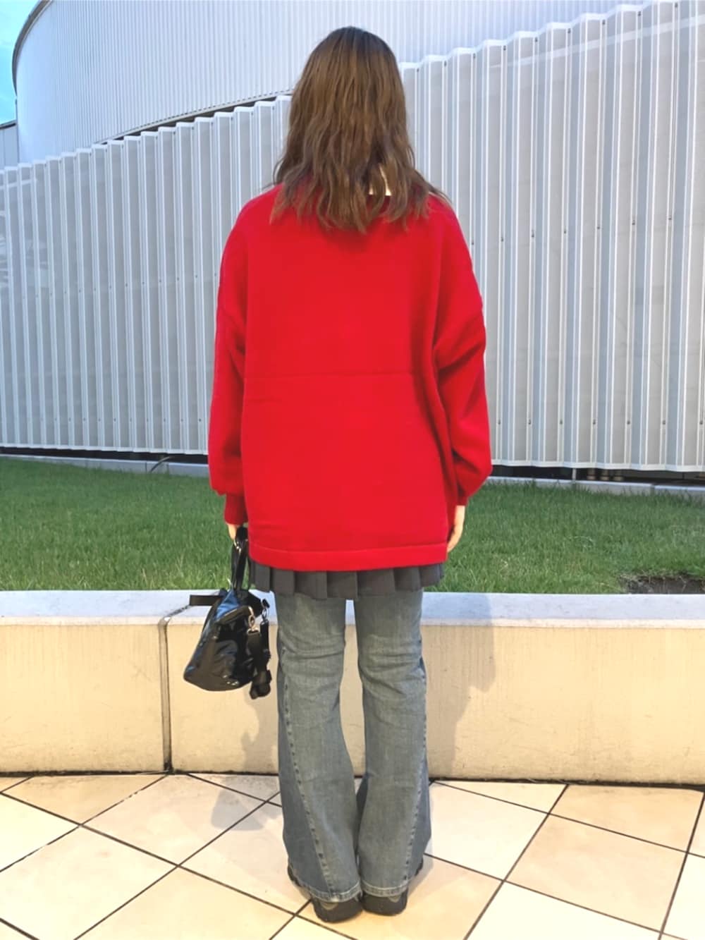 レッド系のカーディガン/ボレロ、ブラック系のショルダーバッグ、ブルー系のデニムパンツを着用したレディースの夏コーディネートの3枚目の写真