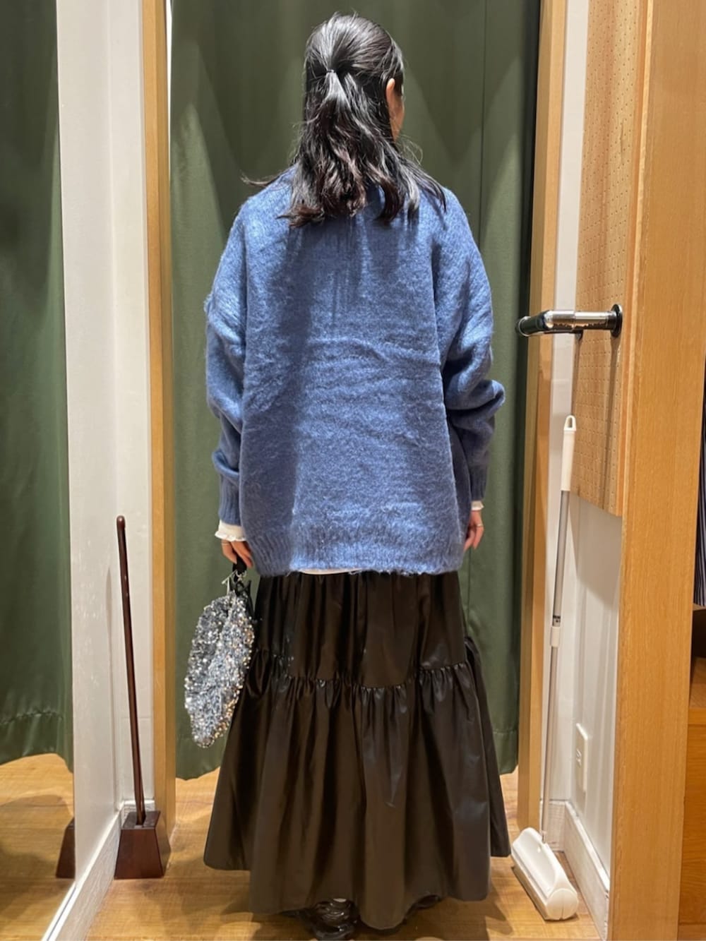 ブラック系のスカート、ブルー系のニット/セーター、シルバー系のショルダーバッグを着用したレディースの夏コーディネートの3枚目の写真