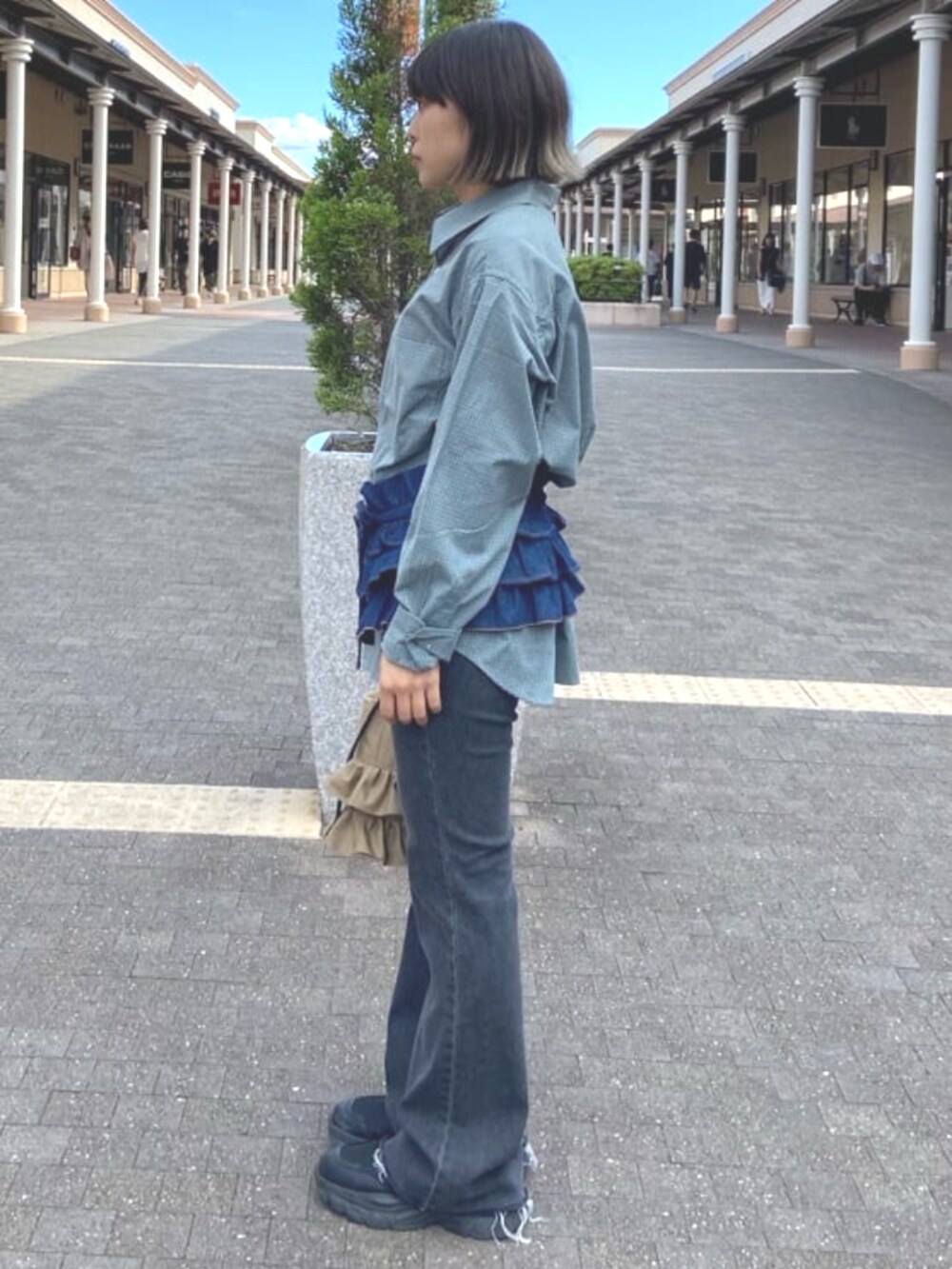 ベージュ系のショルダーバッグ、ブルー系のシャツ/ブラウス、ブラック系のデニムパンツを着用したレディースの夏コーディネートの2枚目の写真