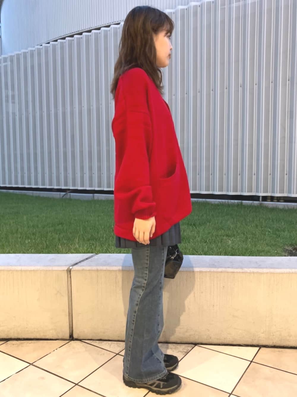 レッド系のカーディガン/ボレロ、ブラック系のショルダーバッグ、ブルー系のデニムパンツを着用したレディースの夏コーディネートの2枚目の写真