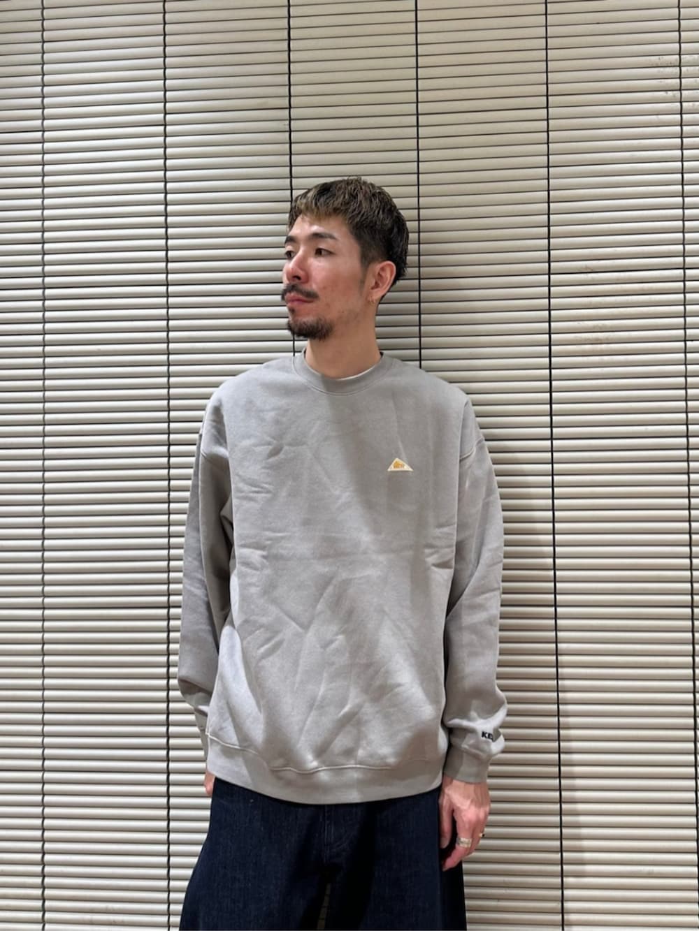 ベージュ系のスウェット、ブルー系のデニムパンツを着用したメンズの秋コーディネートの2枚目の写真