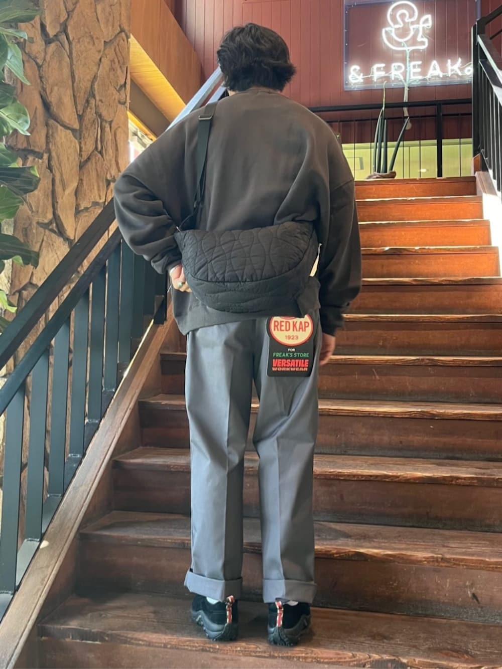 ブラック系のスウェット、ブラック系のショルダーバッグ、グレー系のチノパンツを着用したメンズの秋コーディネートの3枚目の写真