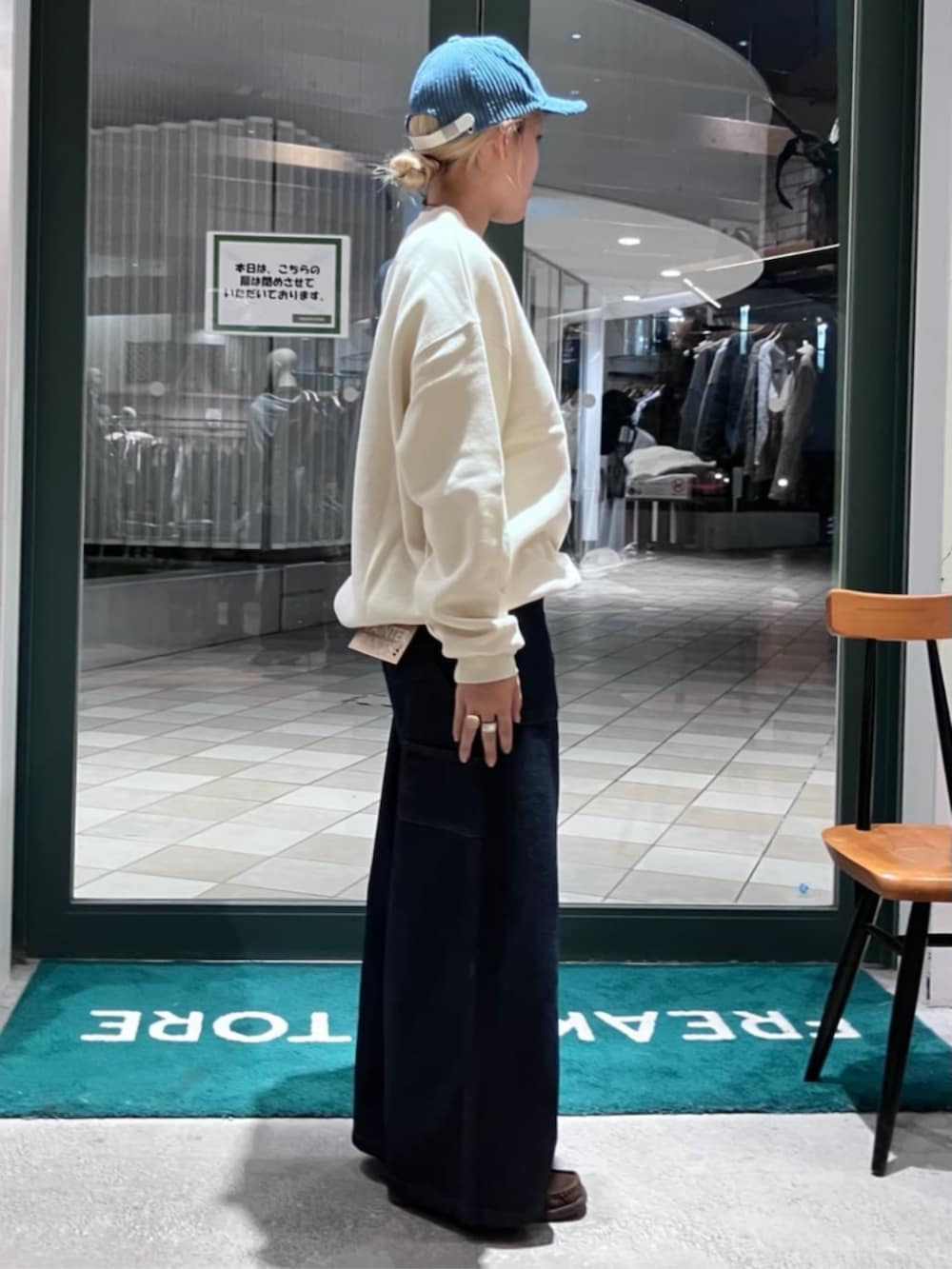 ホワイト系のスウェット、ブルー系のカーゴパンツ、ブルー系のキャップを着用したレディースの秋コーディネートの2枚目の写真