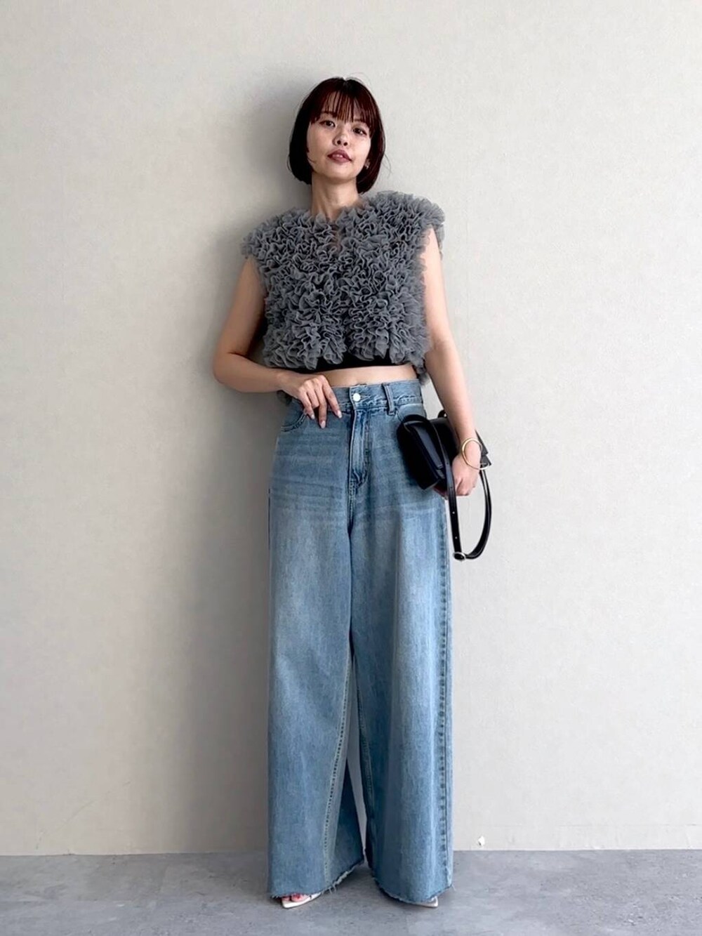 ホワイト系のサンダル、ブルー系のデニムパンツ、ブラック系のショルダーバッグを着用したレディースの夏コーディネートの4枚目の写真