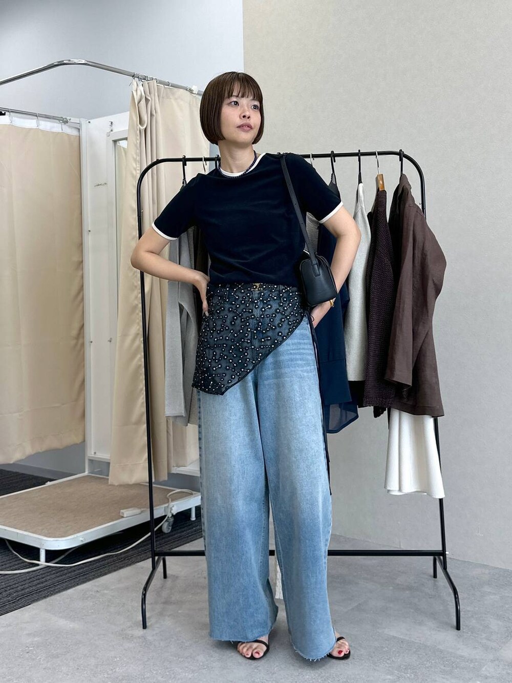 ブルー系のデニムパンツ、ブラック系のハンドバッグ、ブラウン系のサンダルを着用したレディースの春コーディネートの2枚目の写真