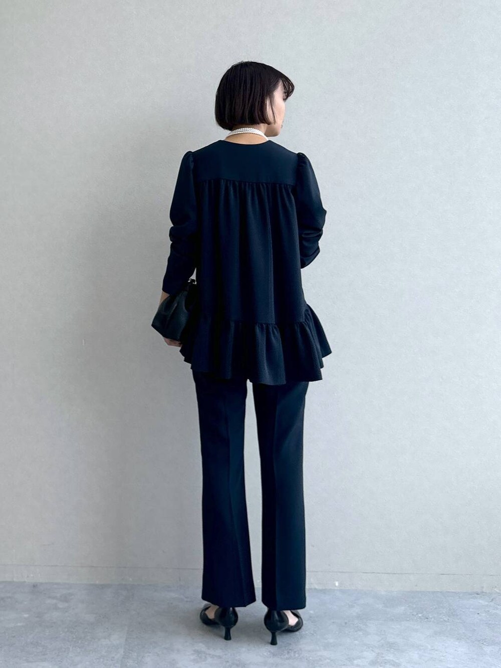 ブラック系のパンプス、ブラック系のショルダーバッグ、ブルー系のスーツセットを着用したレディースの冬コーディネートの4枚目の写真