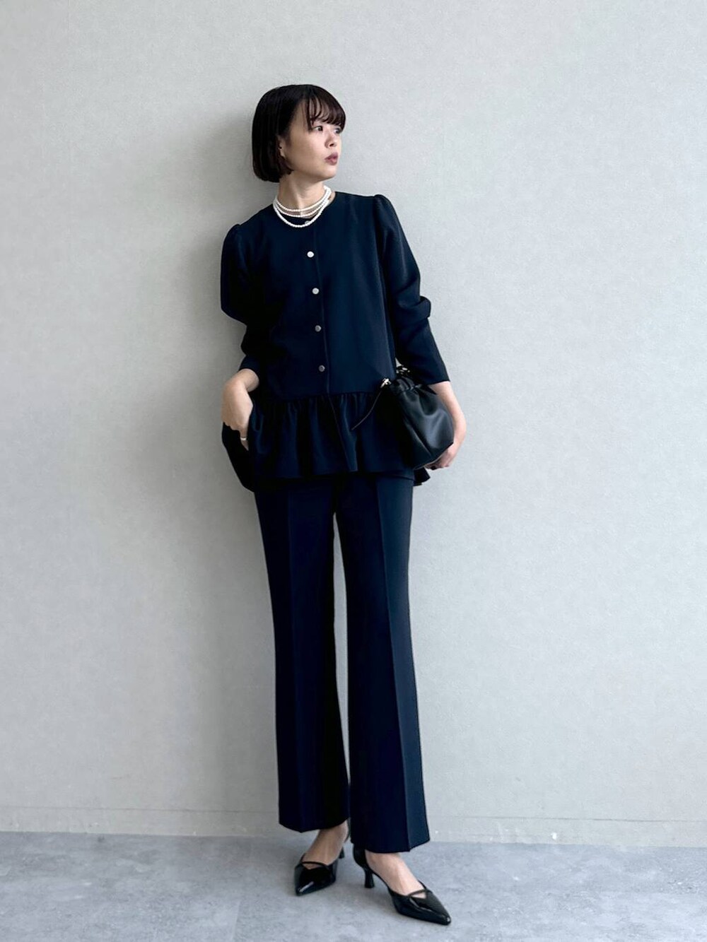 ブラック系のパンプス、ブラック系のショルダーバッグ、ブルー系のスーツセットを着用したレディースの冬コーディネートの2枚目の写真