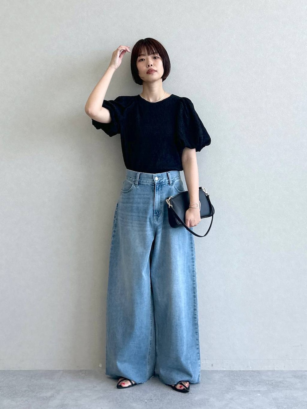 ブルー系のデニムパンツ、ブラック系のショルダーバッグ、ブラック系のサンダルを着用したレディースの春コーディネートの6枚目の写真