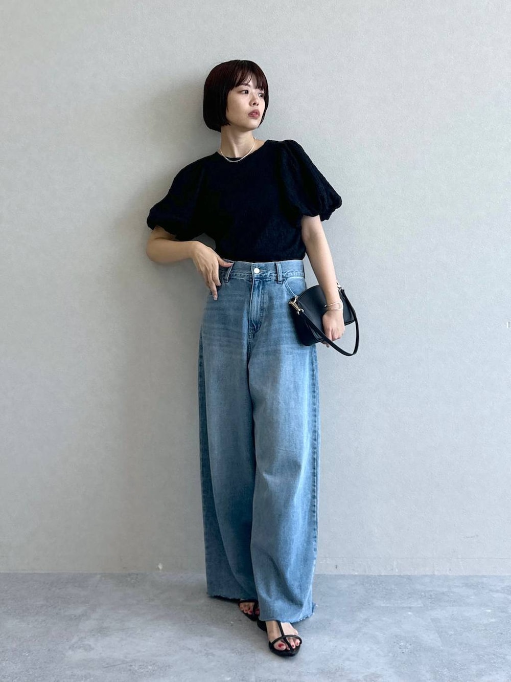 ブルー系のデニムパンツ、ブラック系のショルダーバッグ、ブラック系のサンダルを着用したレディースの春コーディネートの2枚目の写真