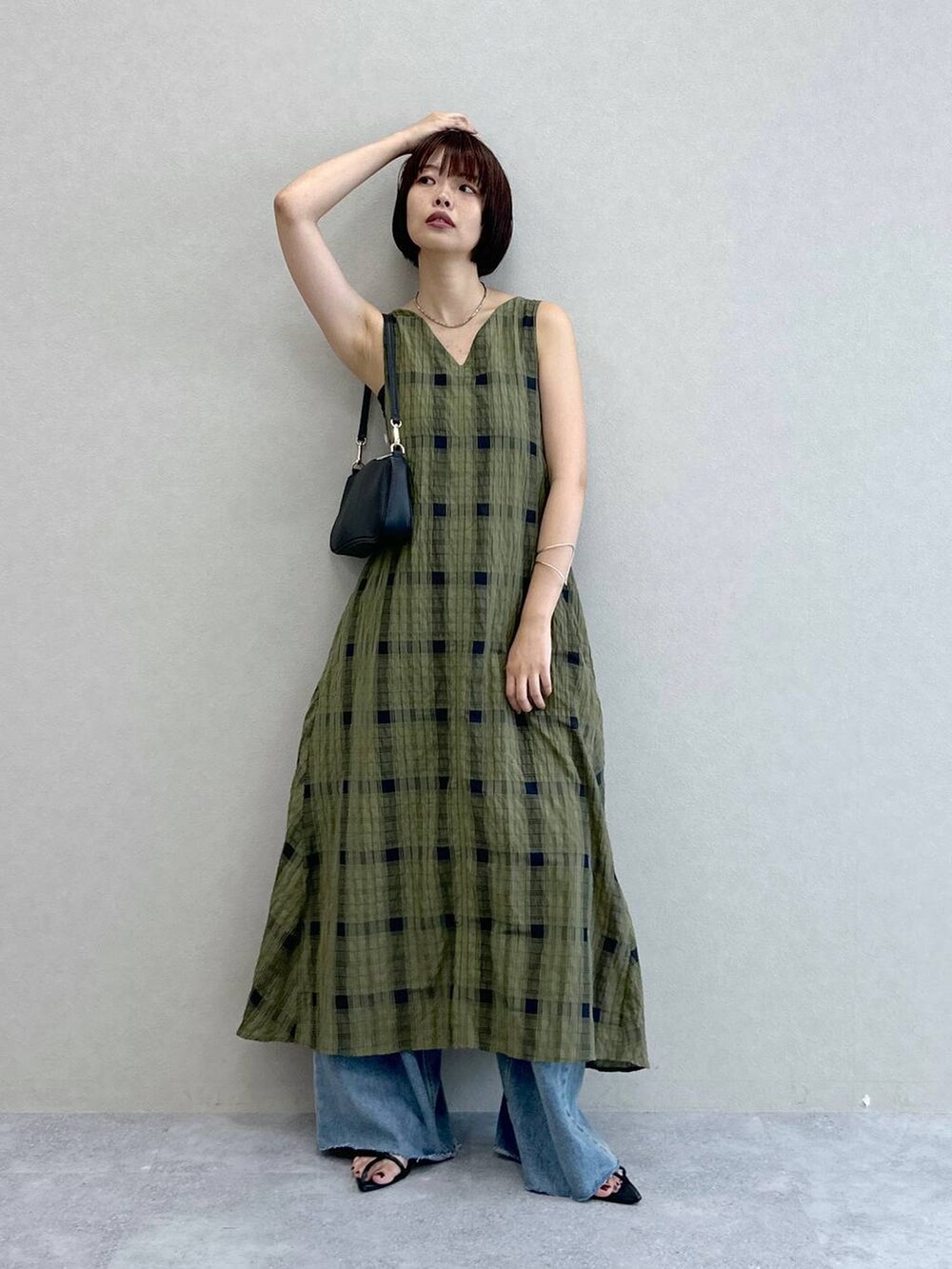 ブルー系のデニムパンツ、グリーン系のワンピース、ブラック系のショルダーバッグを着用したレディースの夏コーディネートの5枚目の写真