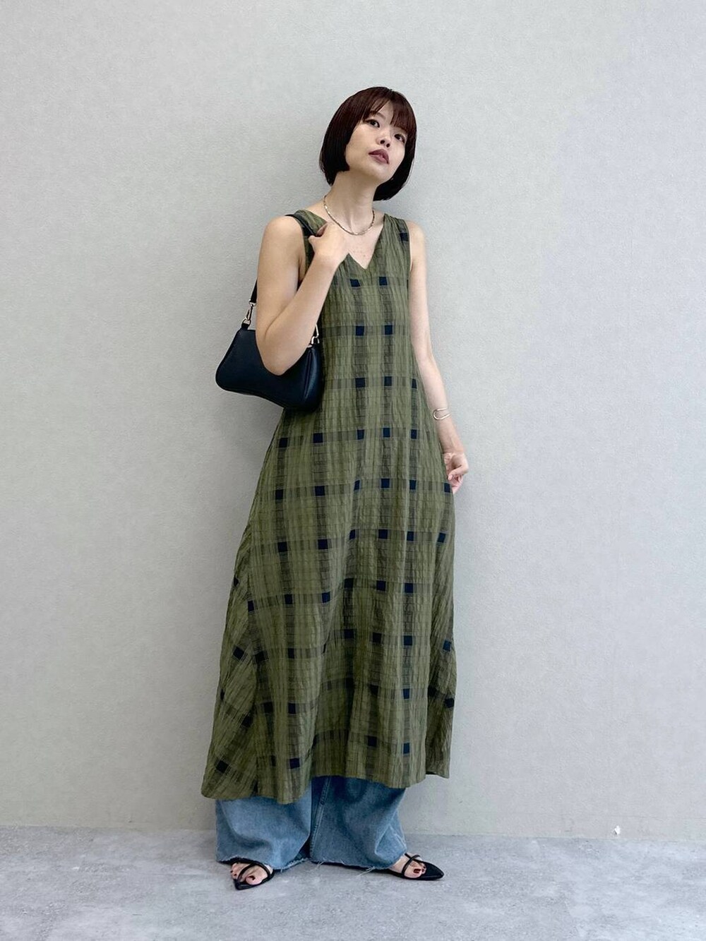 ブルー系のデニムパンツ、グリーン系のワンピース、ブラック系のショルダーバッグを着用したレディースの夏コーディネートの6枚目の写真