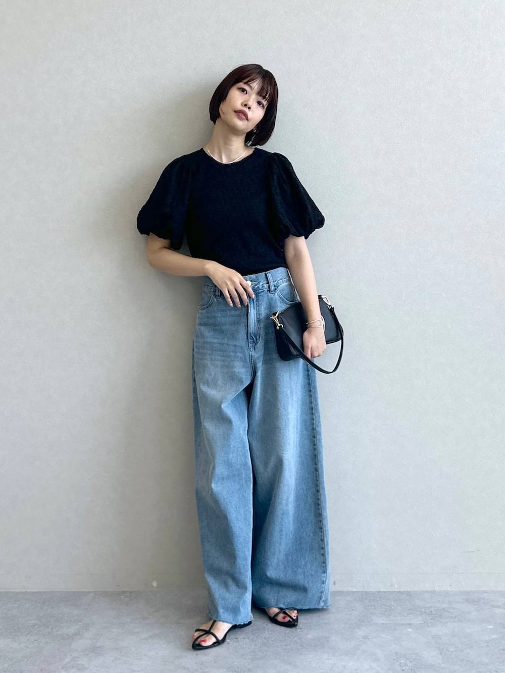 ブルー系のデニムパンツ、ブラック系のショルダーバッグ、ブラック系のサンダルを着用したレディースの春コーディネートの3枚目の写真