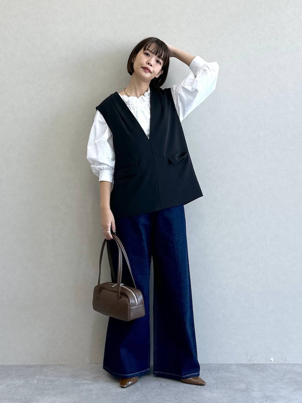 ブラック系のスーツセット、ブルー系のデニムパンツ、ブラウン系のパンプスを着用したレディースの冬コーディネートの2枚目の写真
