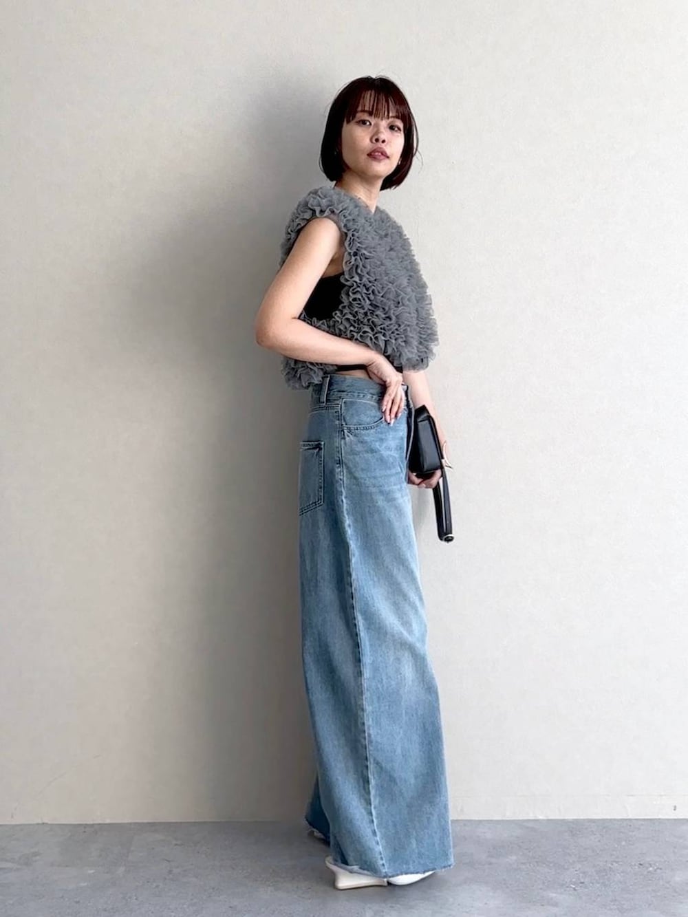 ホワイト系のサンダル、ブルー系のデニムパンツ、ブラック系のショルダーバッグを着用したレディースの夏コーディネートの2枚目の写真