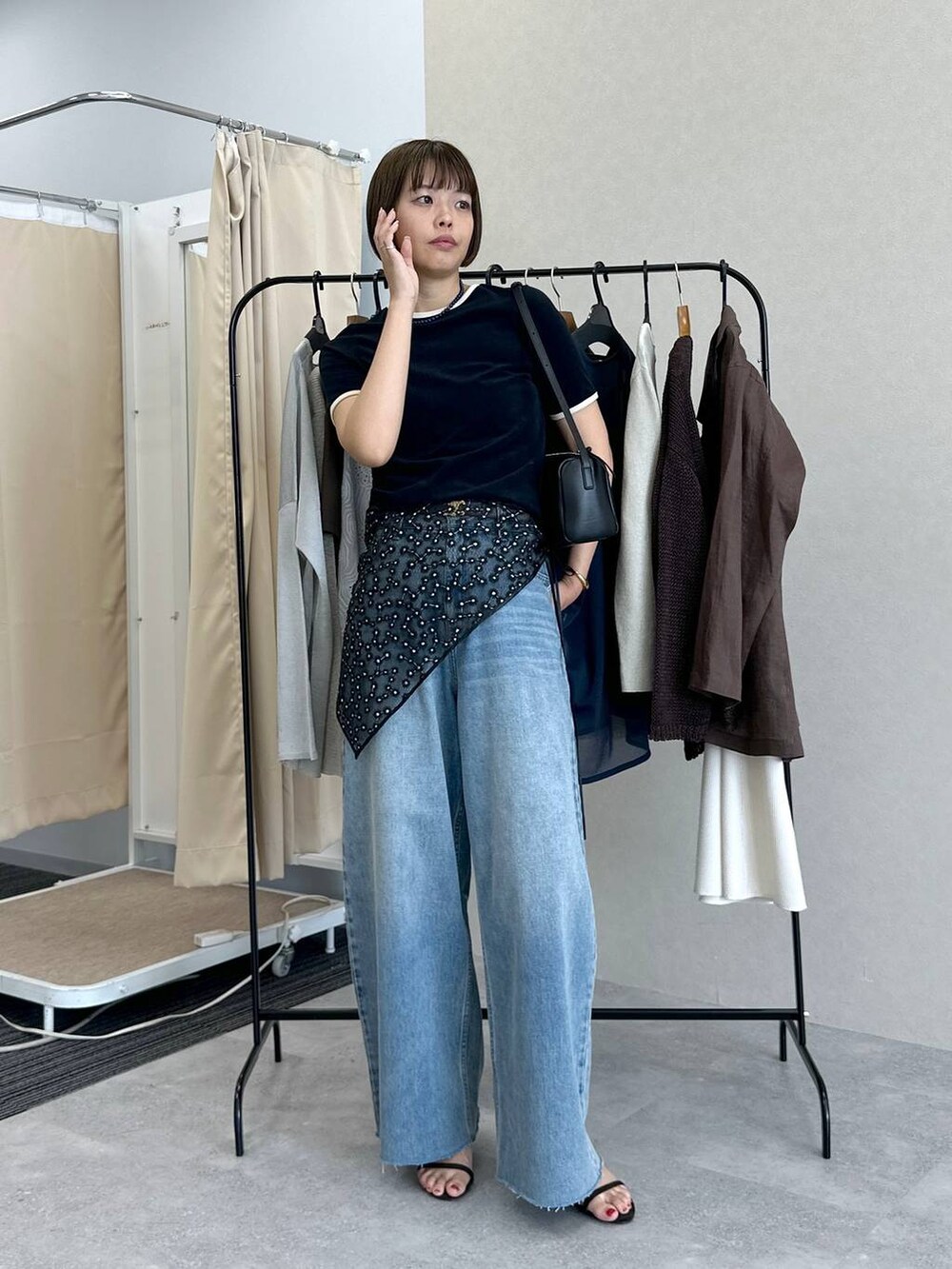 ブルー系のデニムパンツ、ブラック系のハンドバッグ、ブラウン系のサンダルを着用したレディースの春コーディネートの4枚目の写真