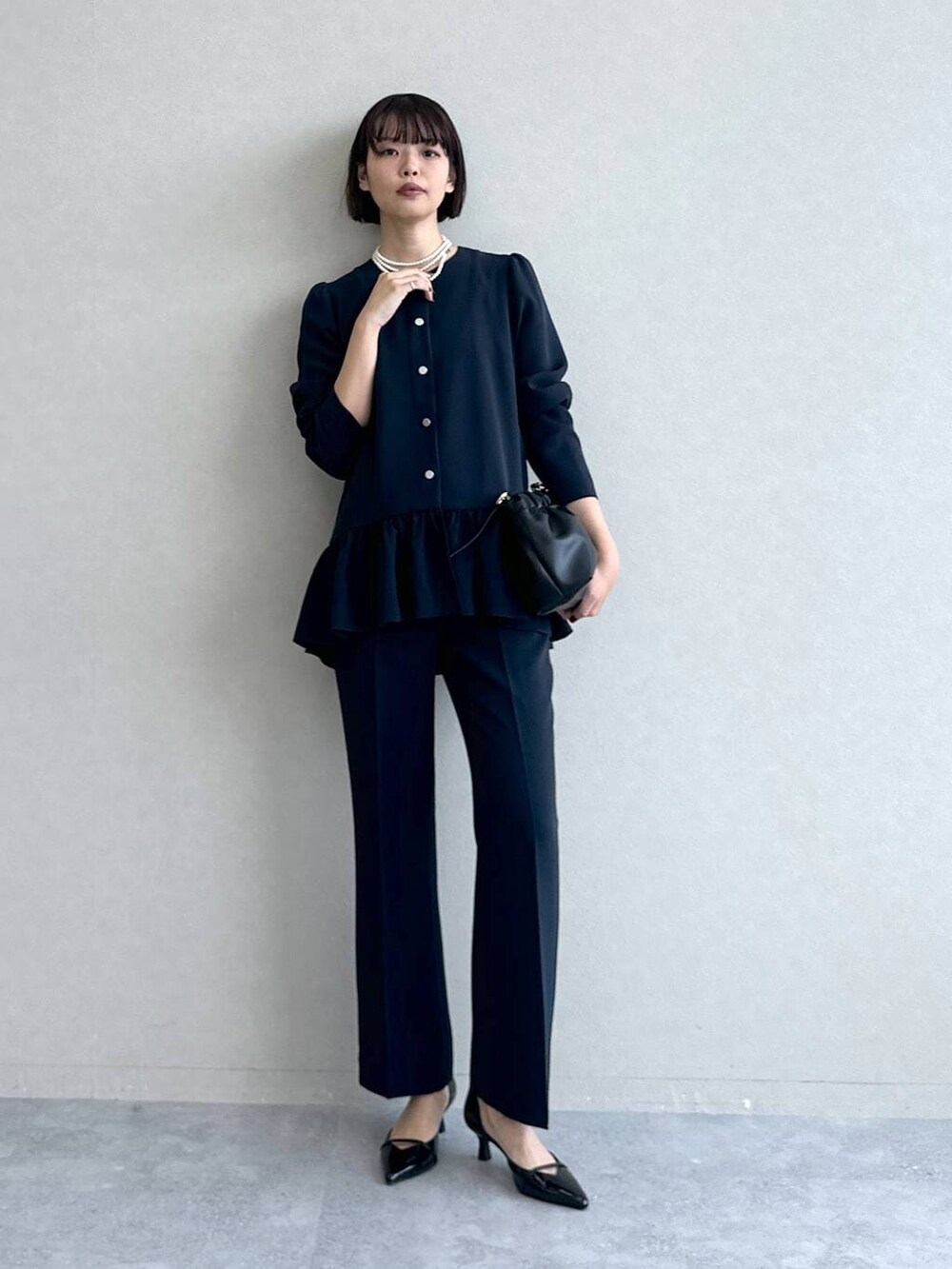 ブラック系のパンプス、ブラック系のショルダーバッグ、ブルー系のスーツセットを着用したレディースの冬コーディネートの6枚目の写真