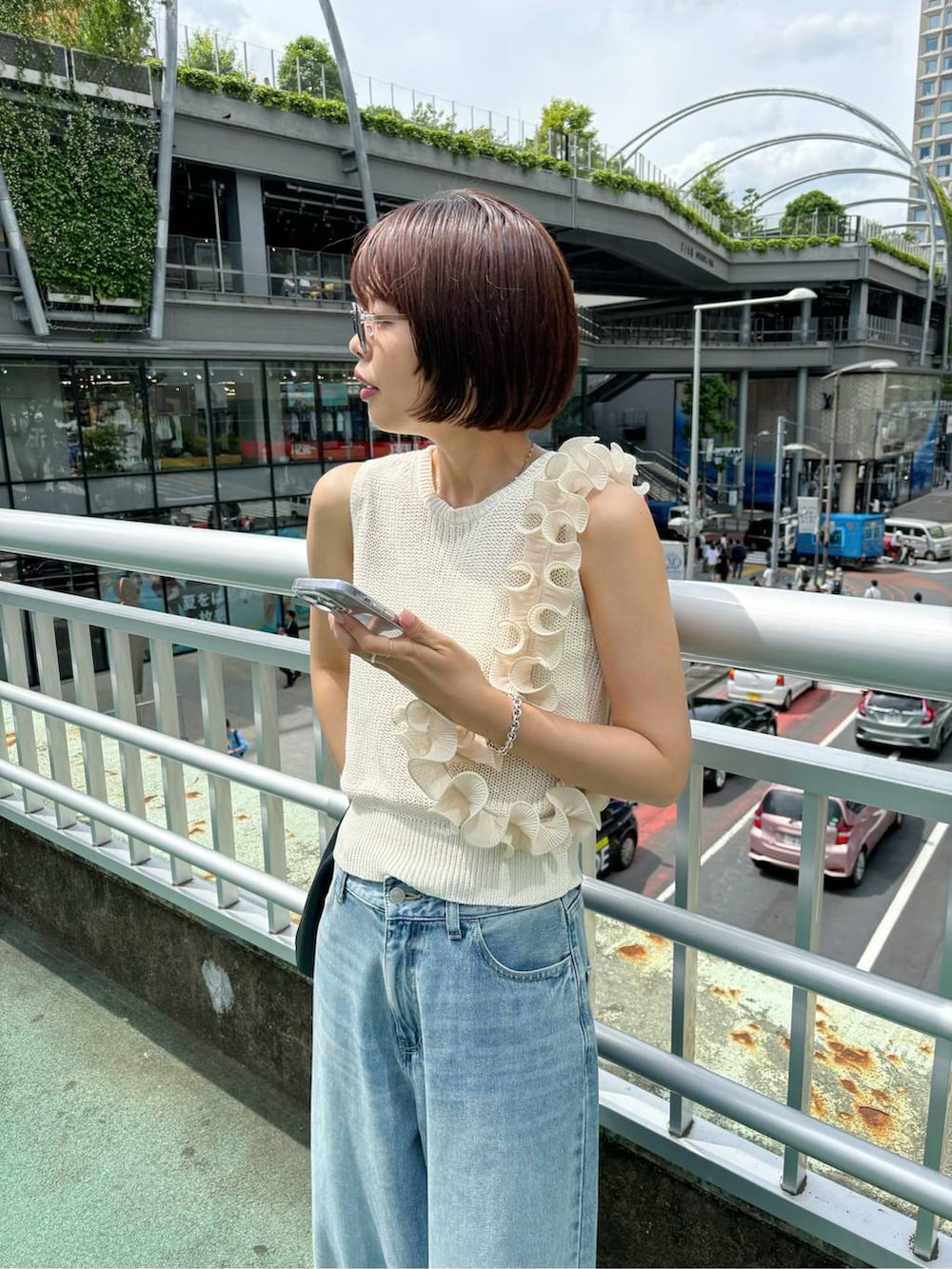 ホワイト系のタンクトップ、ブルー系のデニムパンツ、グレー系のサングラスを着用したレディースの夏コーディネートの4枚目の写真