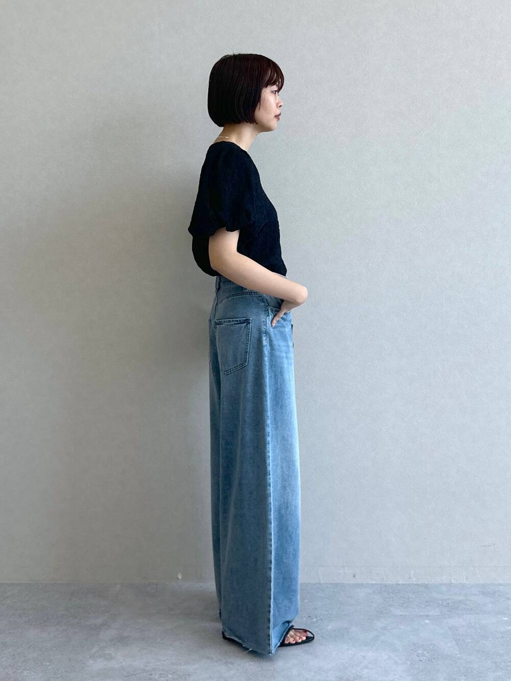 ブルー系のデニムパンツ、ブラック系のショルダーバッグ、ブラック系のサンダルを着用したレディースの春コーディネートの5枚目の写真