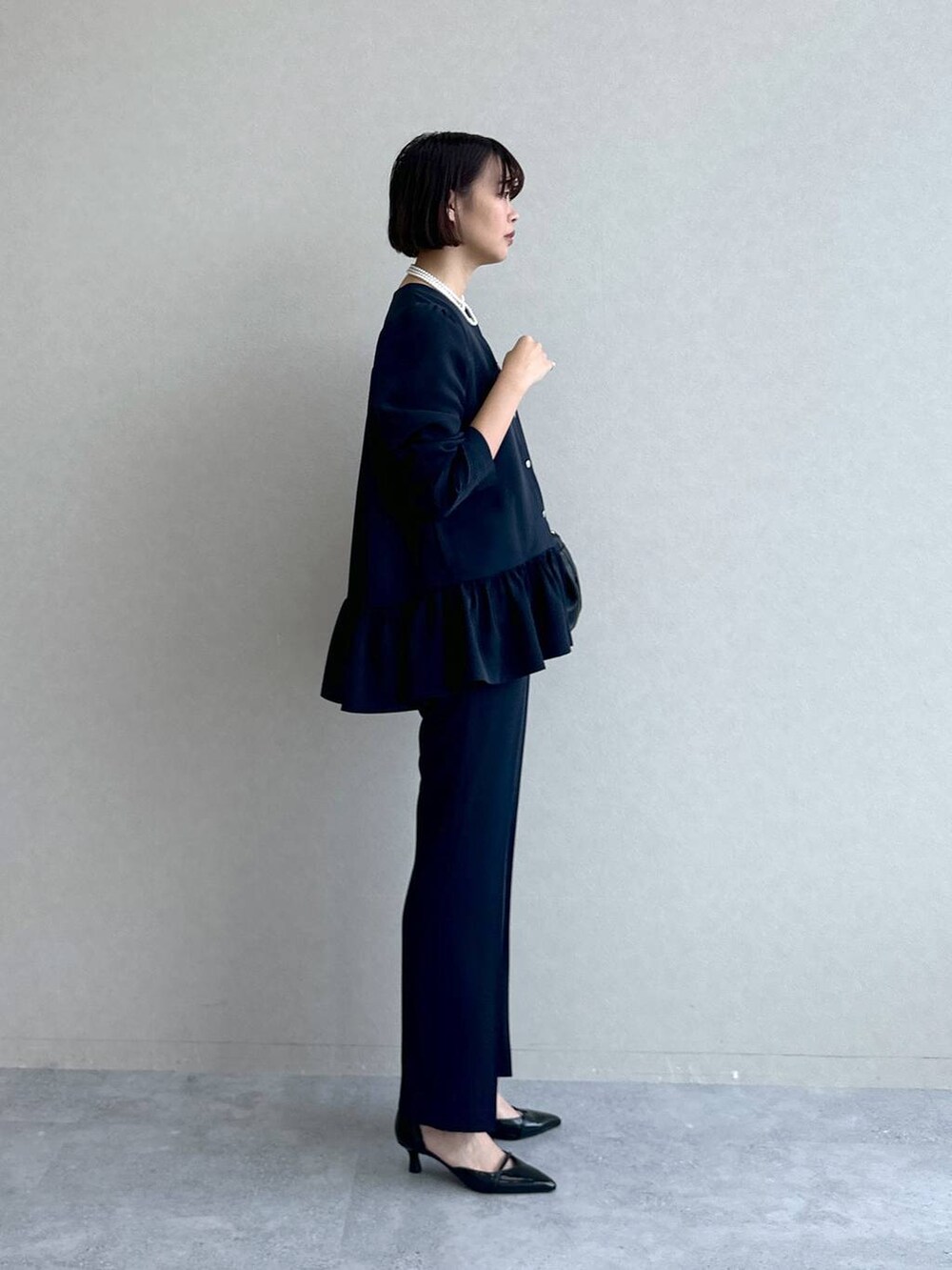 ブラック系のパンプス、ブラック系のショルダーバッグ、ブルー系のスーツセットを着用したレディースの冬コーディネートの5枚目の写真