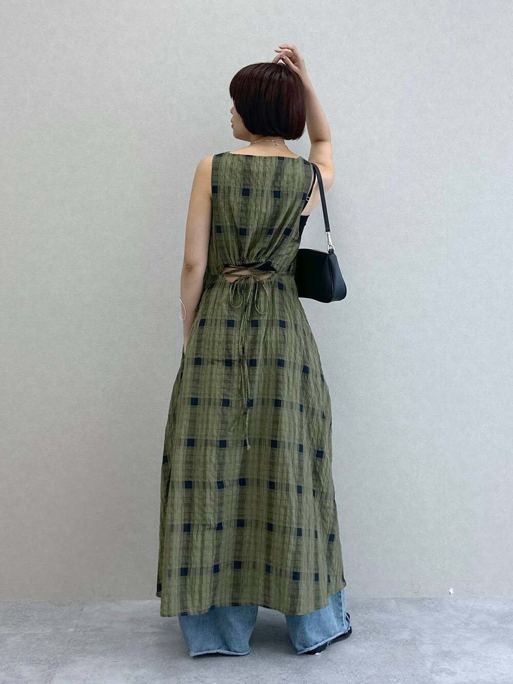 ブルー系のデニムパンツ、グリーン系のワンピース、ブラック系のショルダーバッグを着用したレディースの夏コーディネートの3枚目の写真