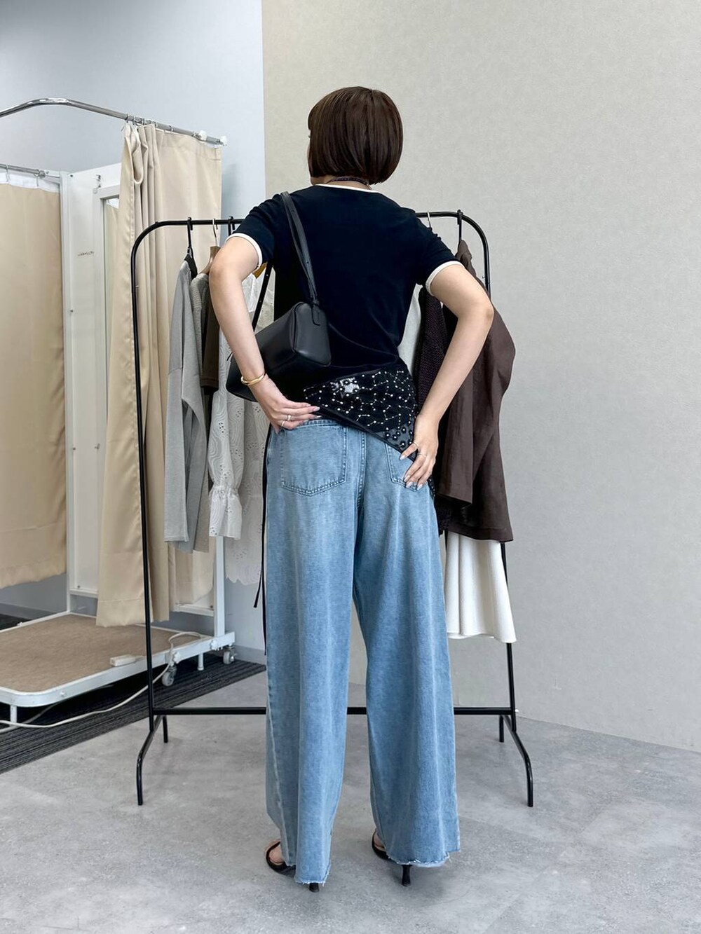 ブルー系のデニムパンツ、ブラック系のハンドバッグ、ブラウン系のサンダルを着用したレディースの春コーディネートの3枚目の写真