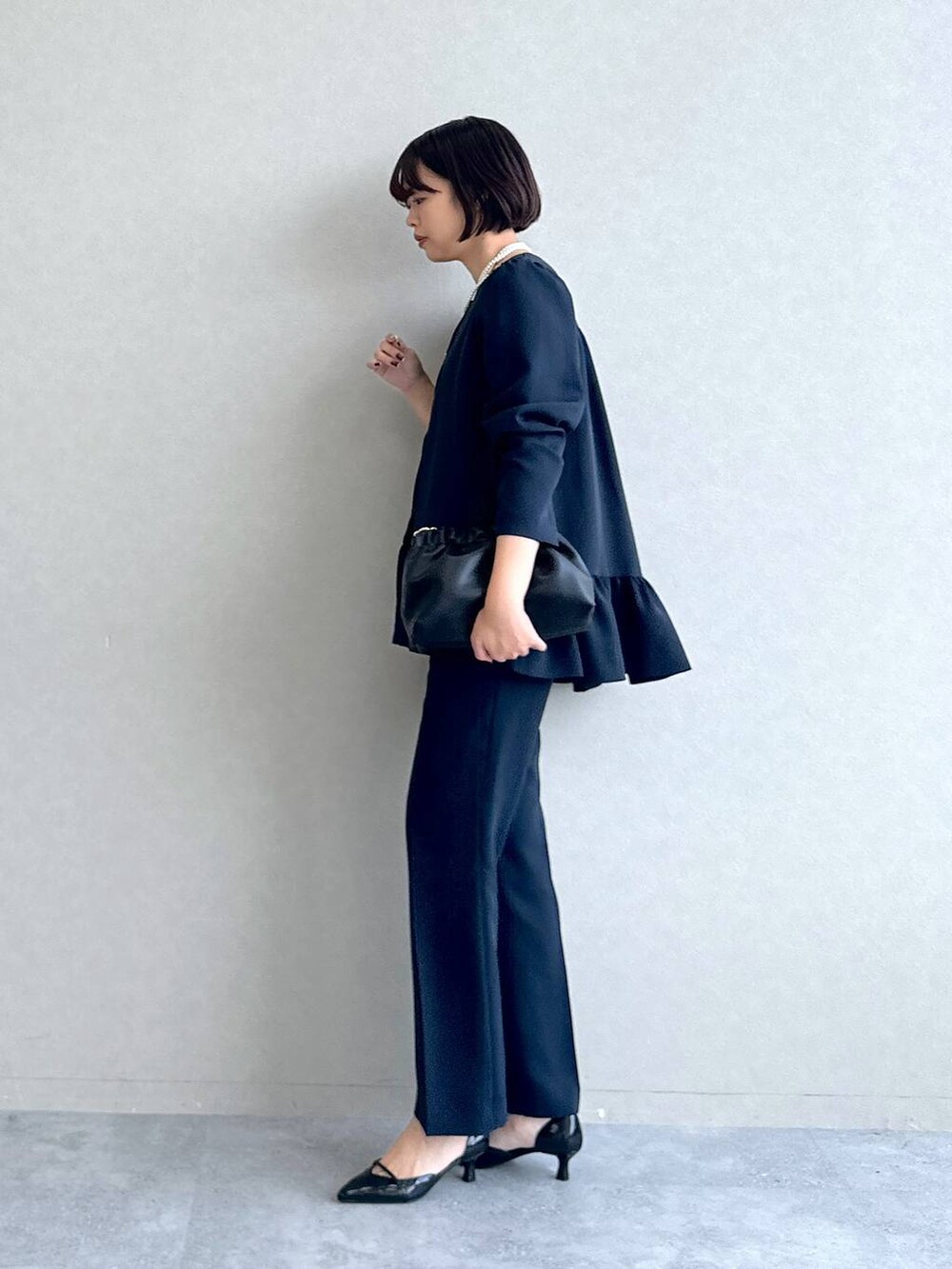 ブラック系のパンプス、ブラック系のショルダーバッグ、ブルー系のスーツセットを着用したレディースの冬コーディネートの3枚目の写真