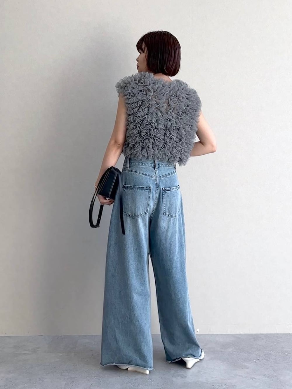 ホワイト系のサンダル、ブルー系のデニムパンツ、ブラック系のショルダーバッグを着用したレディースの夏コーディネートの3枚目の写真