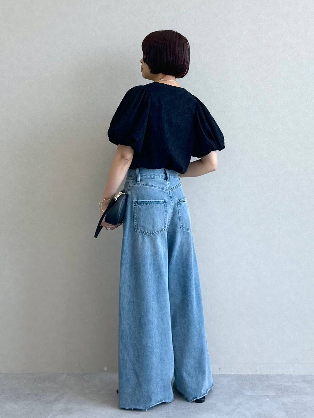 ブルー系のデニムパンツ、ブラック系のショルダーバッグ、ブラック系のサンダルを着用したレディースの春コーディネートの4枚目の写真