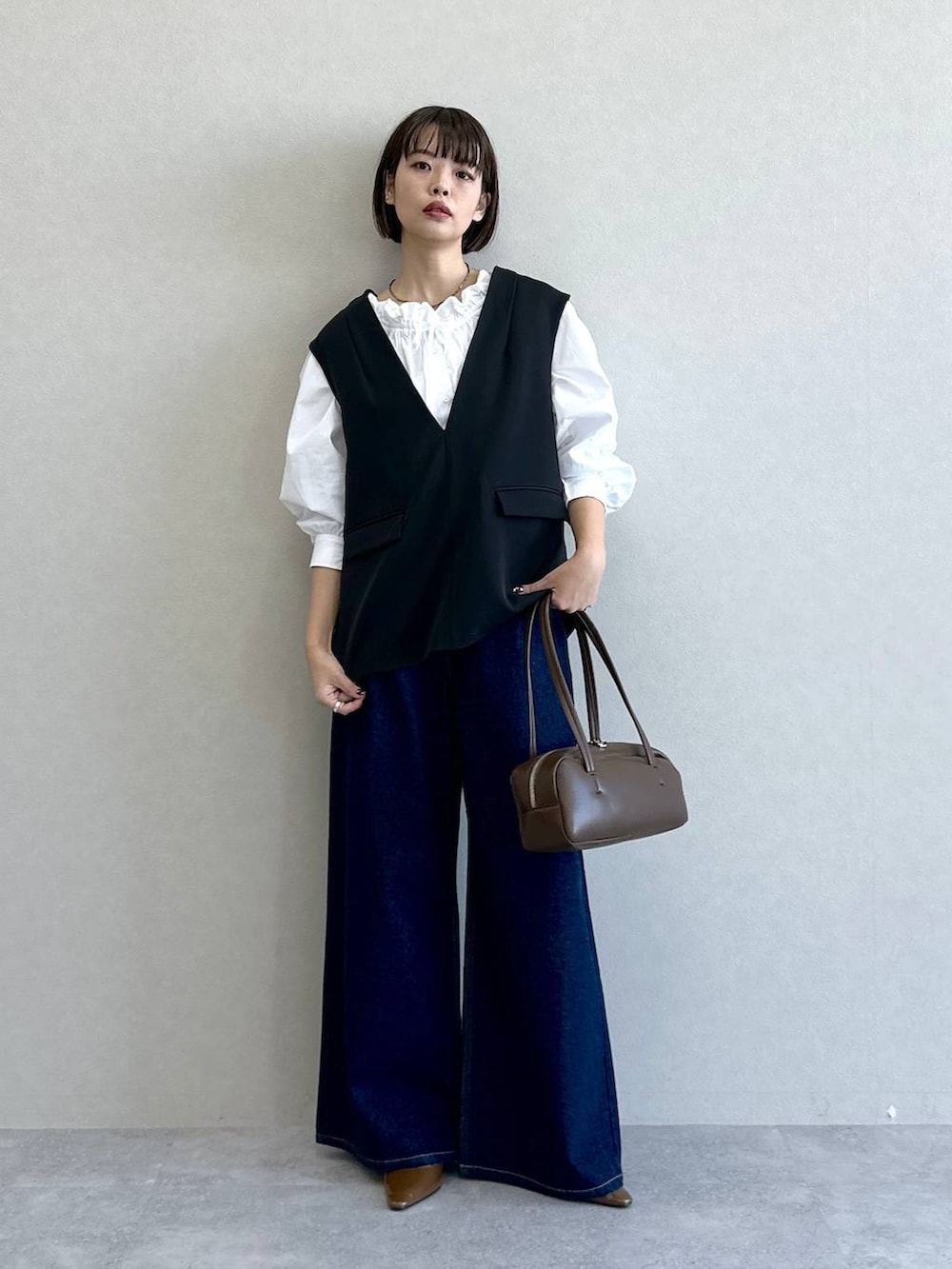 ブラック系のスーツセット、ブルー系のデニムパンツ、ブラウン系のパンプスを着用したレディースの冬コーディネートの4枚目の写真