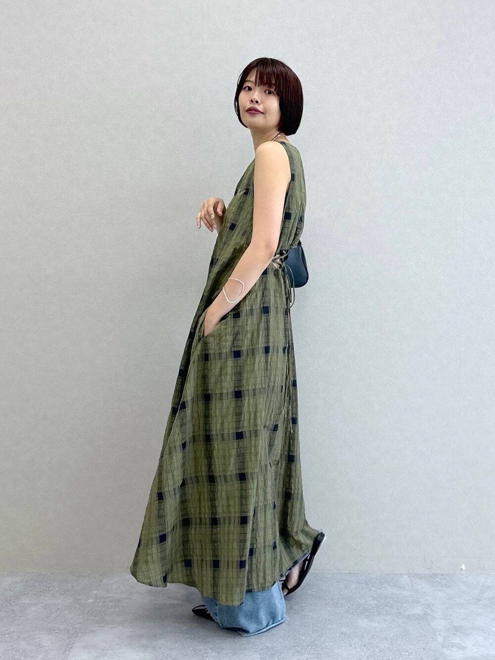 ブルー系のデニムパンツ、グリーン系のワンピース、ブラック系のショルダーバッグを着用したレディースの夏コーディネートの4枚目の写真