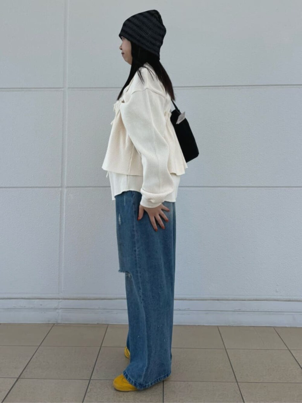 ブラック系のハンドバッグ、ブルー系のデニムパンツ、ホワイト系のTシャツ/カットソーを着用したレディースの春コーディネートの2枚目の写真