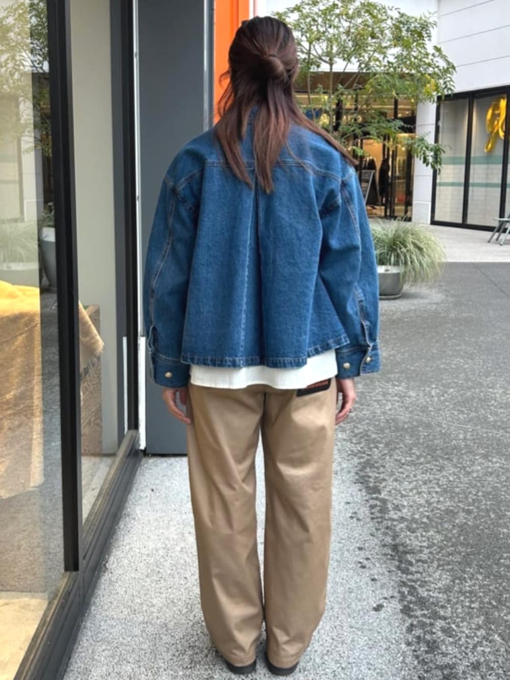 ブルー系のデニムジャケット、ベージュ系のチノパンツ、ベージュ系のTシャツ/カットソーを着用したレディースの春コーディネートの3枚目の写真